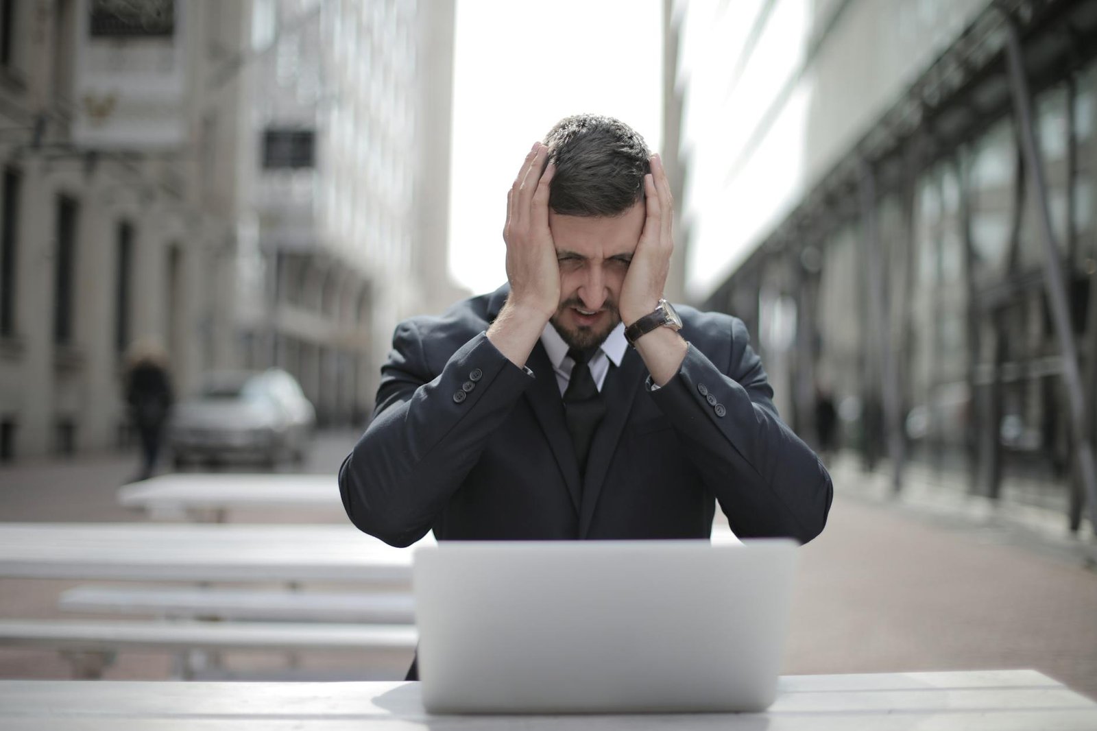 man in black suit covering his face with two hands
